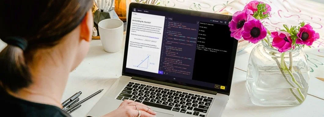 Person working on a laptop beside a vase with flowers