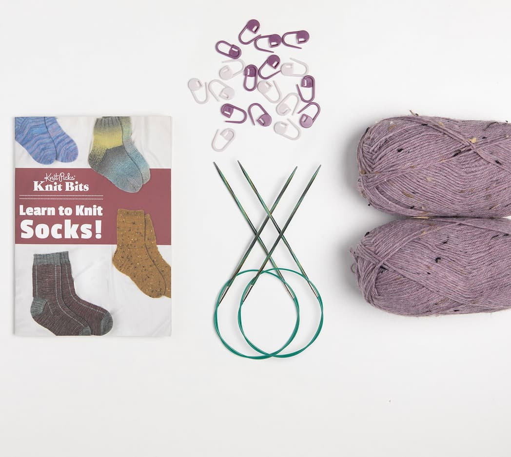 A sock knitting kit with needles, stitch markers, and yarn. >>