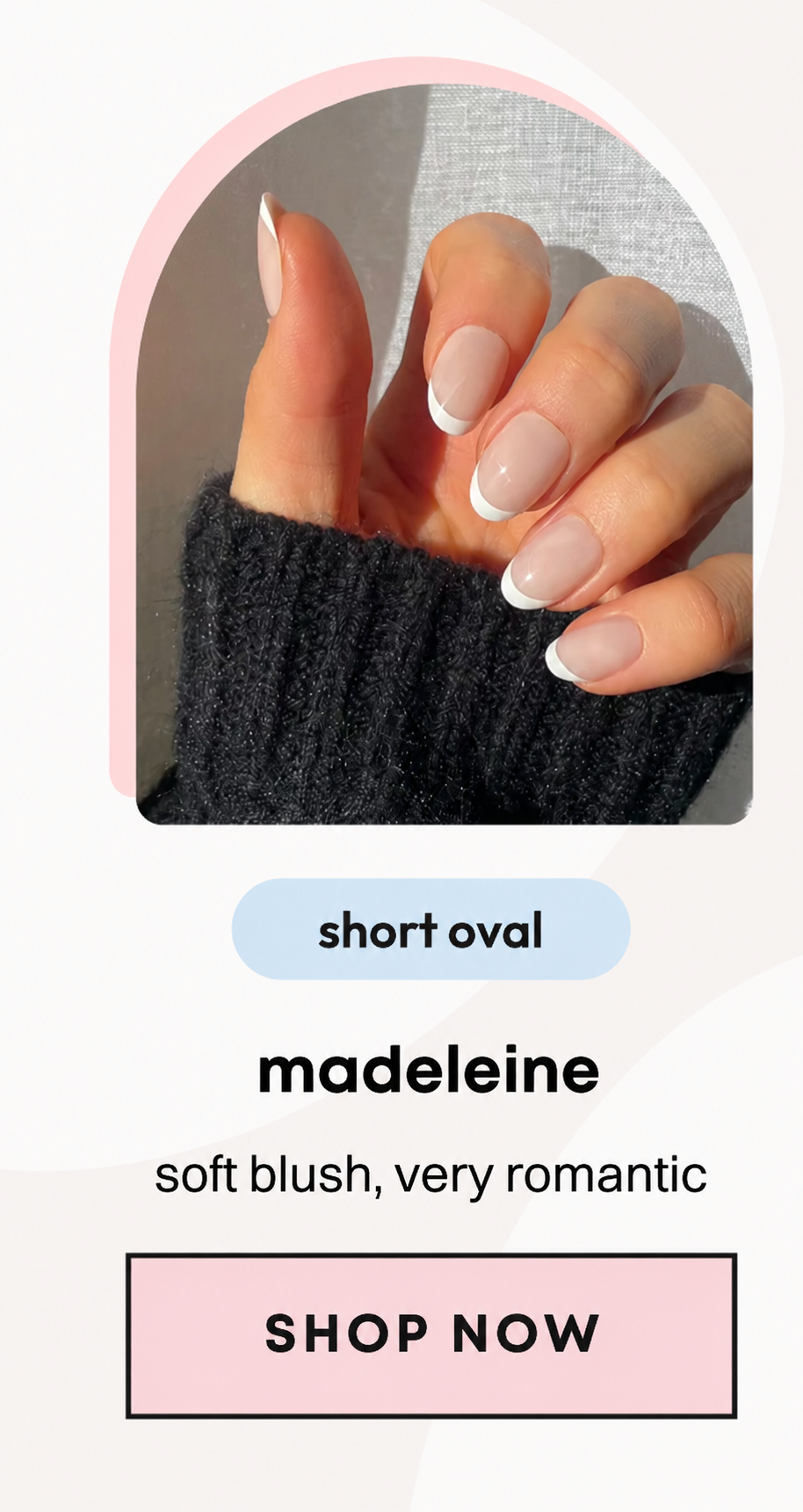 Hand wearing short oval nude press-on nails with white tips against black sweater