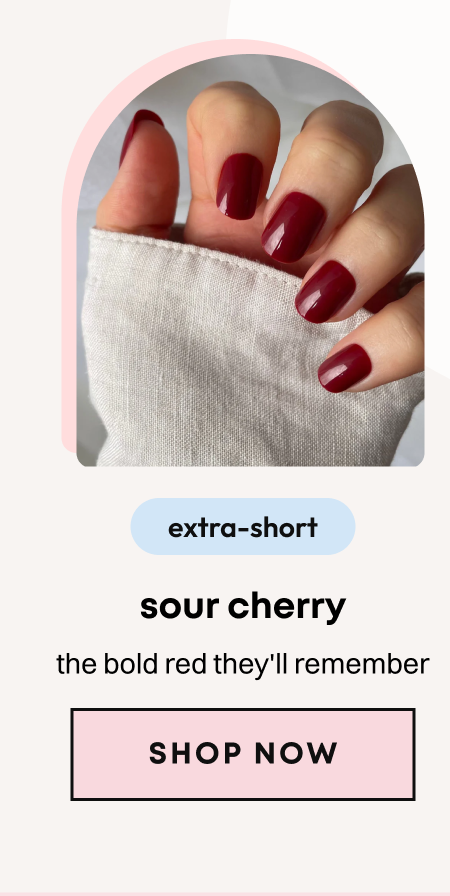 Hand wearing deep red burgundy press-on nails in short oval shape