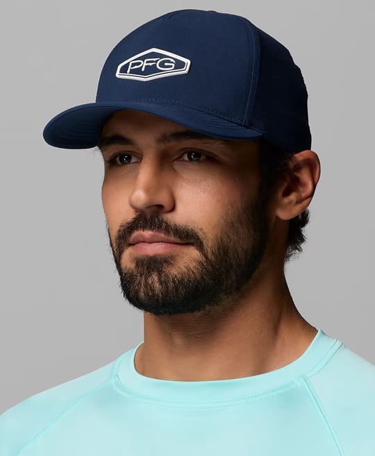 A man wearing a navy blue ball cap with the Columbia PFG logo on the front.