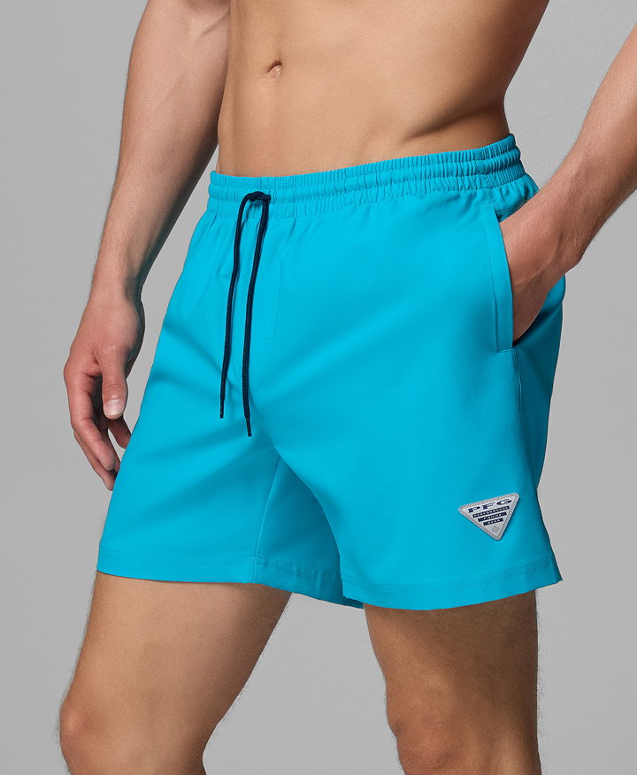 Waist-down image of a man wearing neon blue swim trunks.