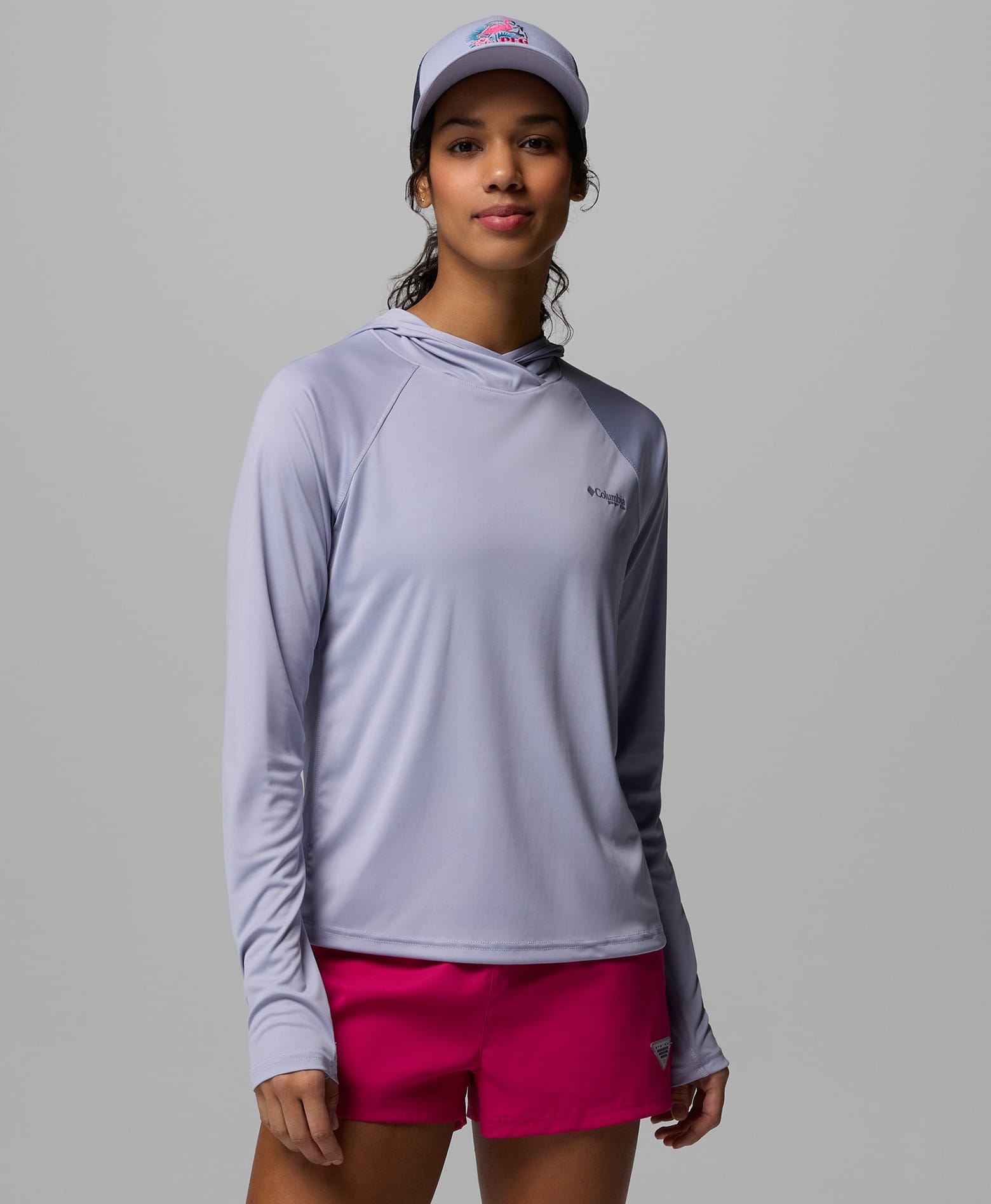 A woman wearing a light purple sun hoodie with a purple ball cap.