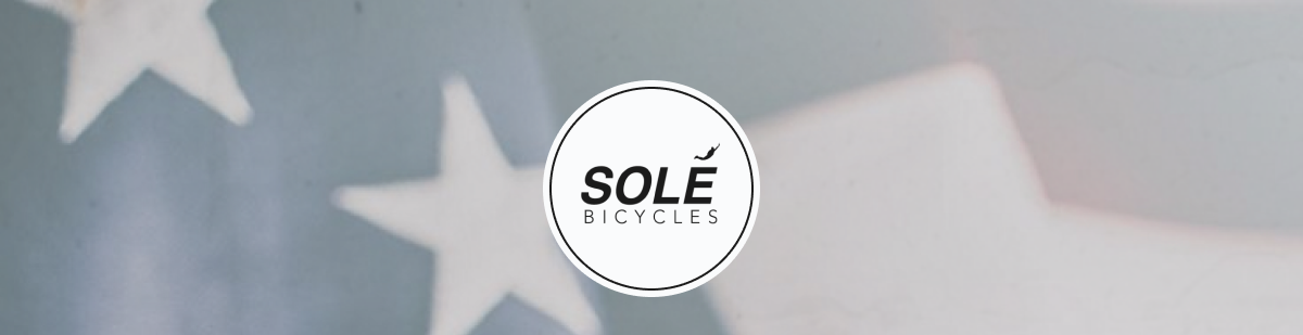 Sole Bicycles logo on a blurred background featuring stars and stripes.