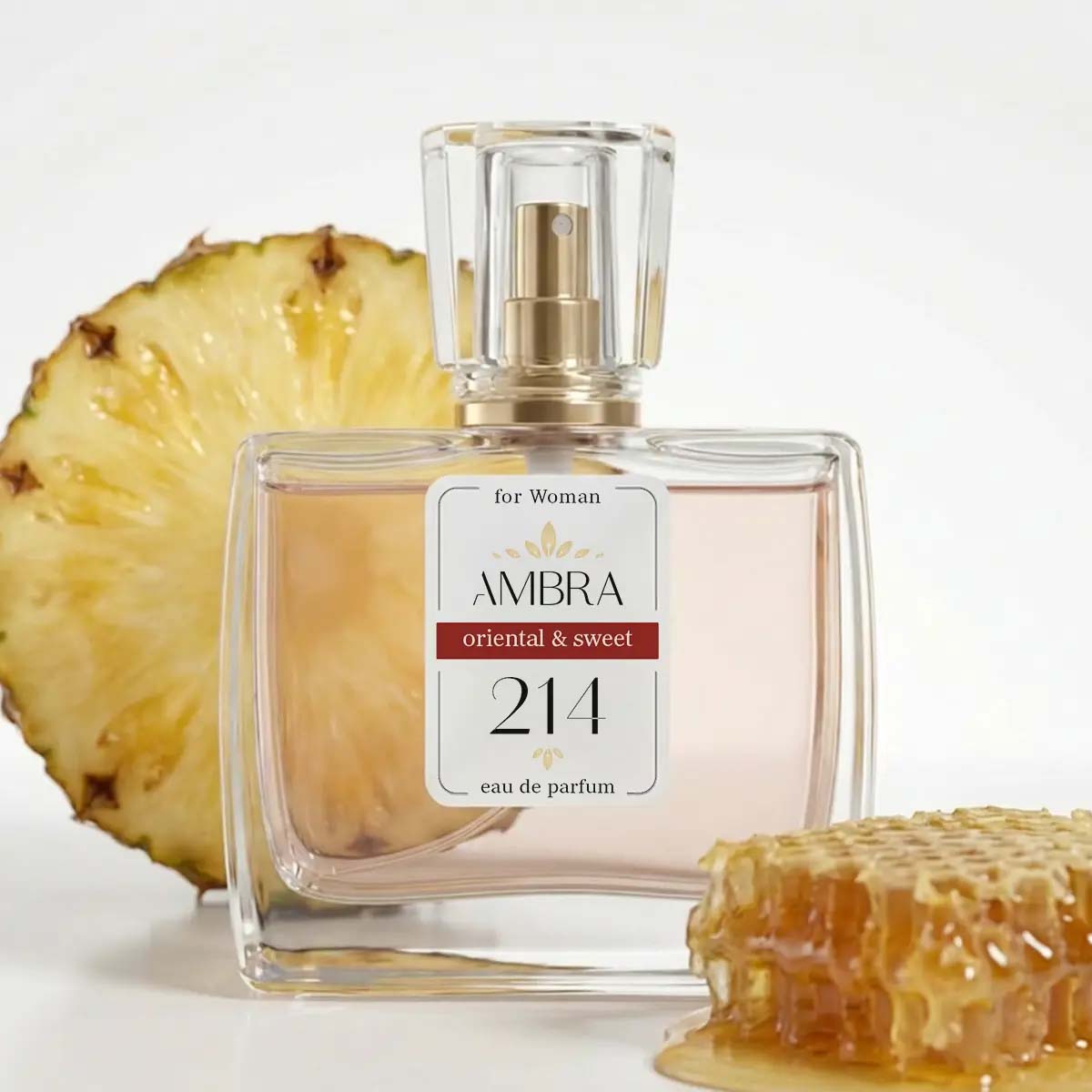 Glass perfume bottle labelled 'AMBRA 214' (oriental & sweet) beside a pineapple slice and dripping honeycomb
