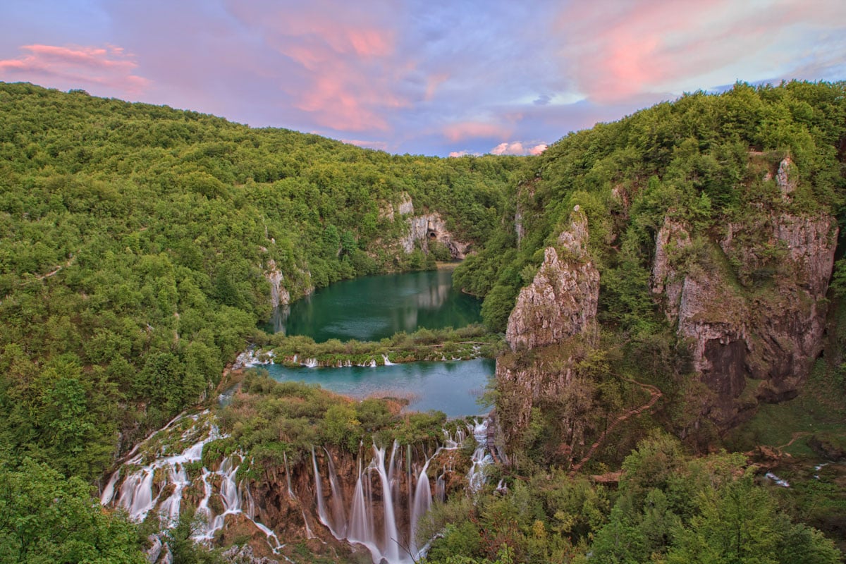 Cascadas del Parque Nacional de Plitvice cayendo en cortinas blancas a un lago turquesa, bosques al fondo