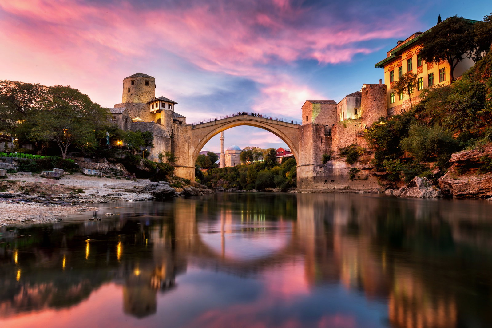 Puente Stari Most de Mostar al atardecer sobre el río Neretva, cielo en tonos rosados