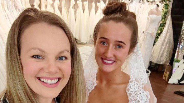 Emily Grant and Venezuela Fury smile at the camera, with Fury in her wedding dress and veil.