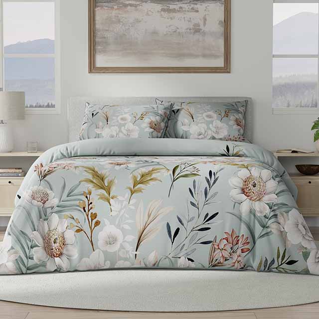 A bed with floral-patterned bedding is set in a light, airy room with a landscape painting above and large windows on either side.