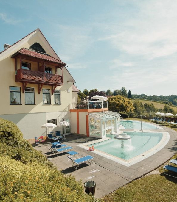 Hotel Außenansicht mit Pool, Liegen und Sonnenschirmen