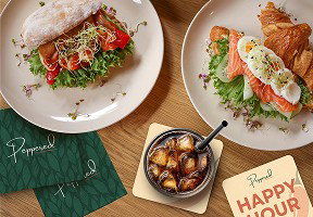 A table displays branded coasters and napkins alongside plated food and drinks.