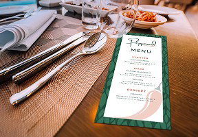 A Peppered menu is set alongside silverware, glassware, and a plate of food in the background.