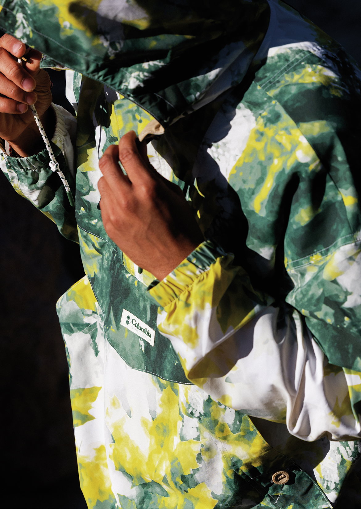 Close up of a man wearing a jacket with splashes of green and yellow. 