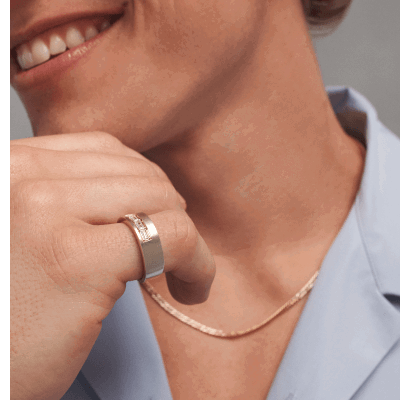 Man wearing gold chain necklace and wide band ring with diamond accent.