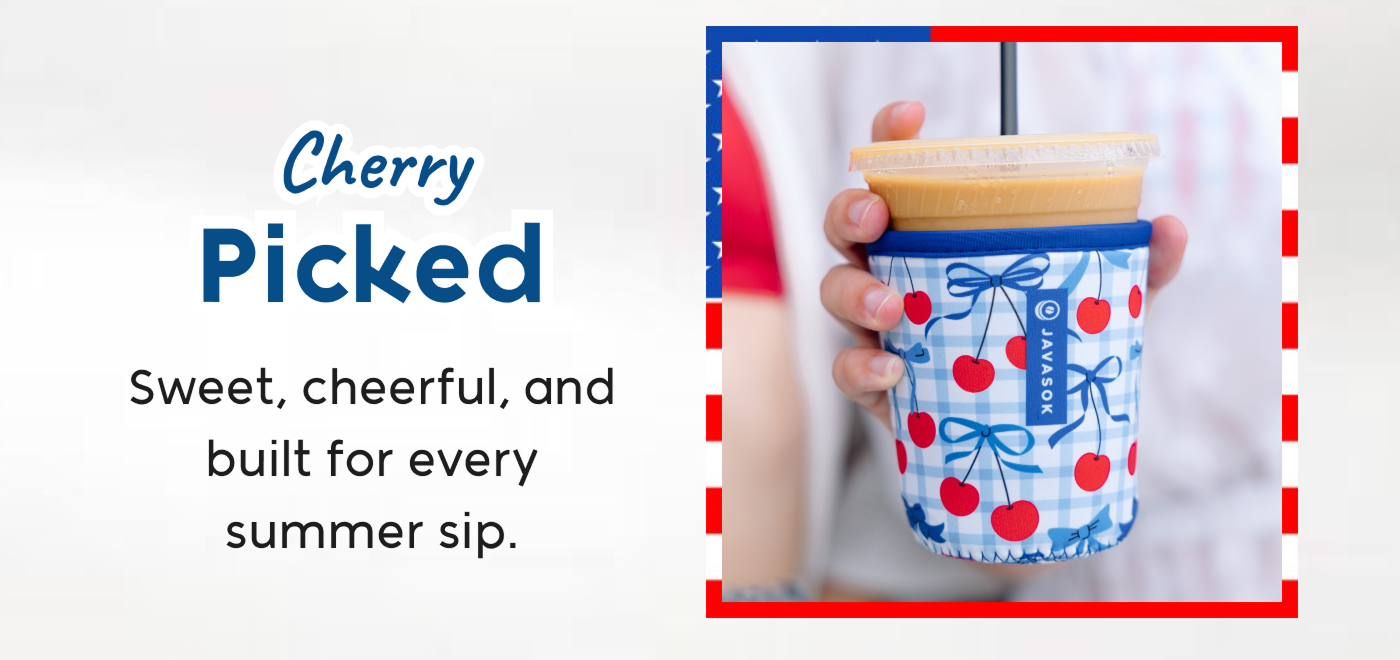 Hand holding a cherry-patterned tumbler with iced drink and reusable straw.