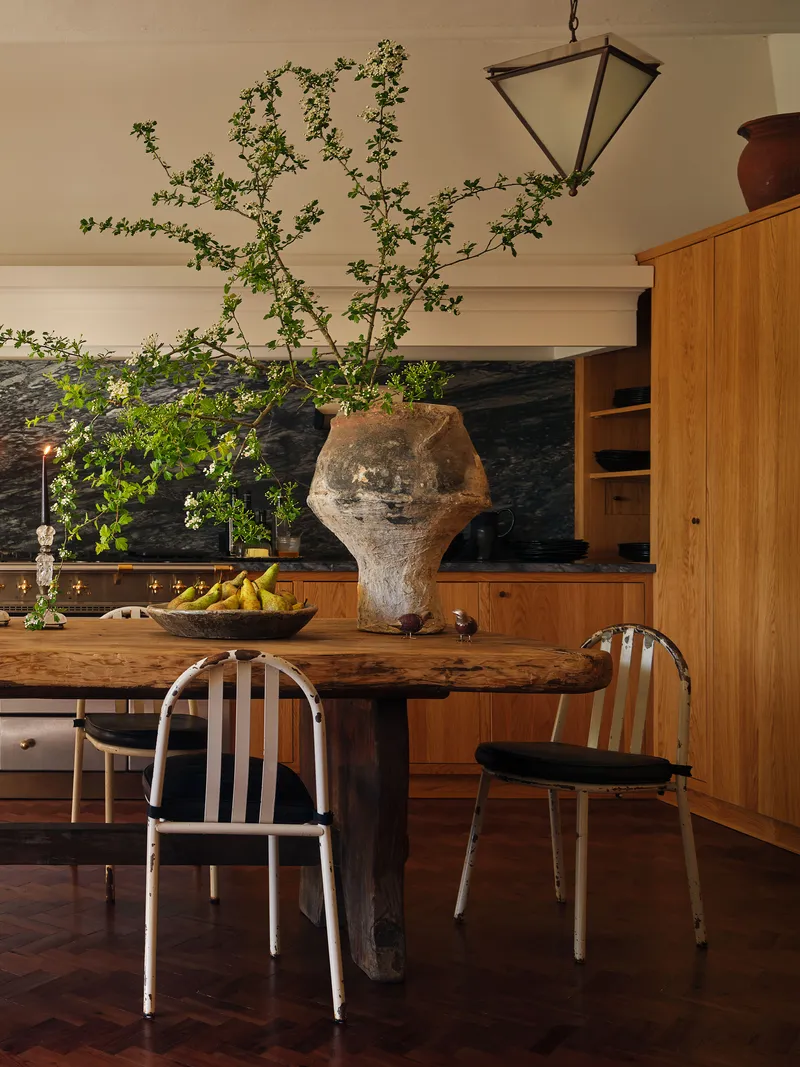 Kitchen with large wood table and dark backsplash behind it.