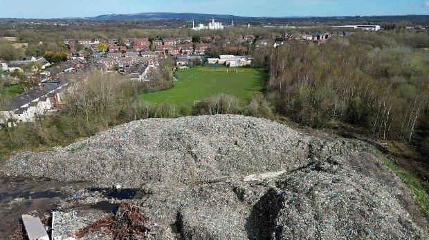 An aerial view shows huge mountain of waste sits among trees by a field and overlooks houses in Bickershaw, near Wigan.