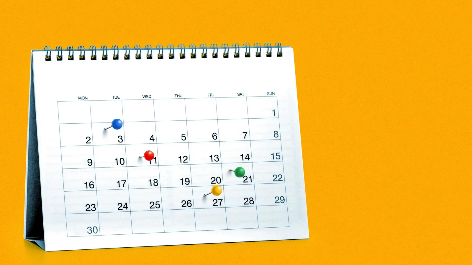 Illustration of a standing desk calendar with a blue pin, a red pin, a yellow pin, and a green pin.