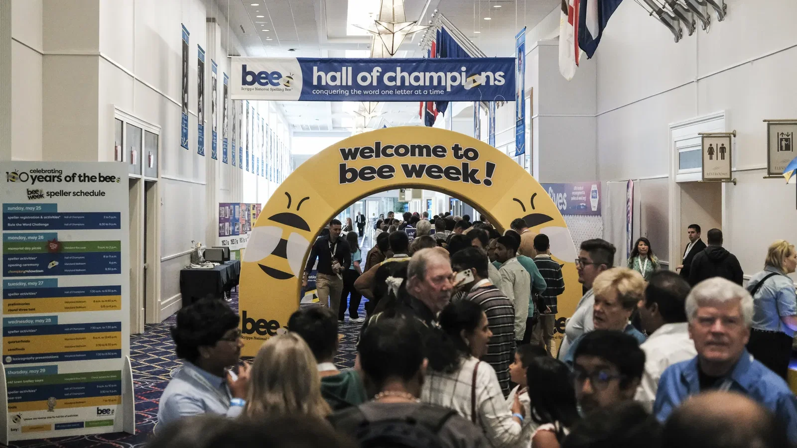 Busy convention hall for a spelling bee; a blue banner reads 