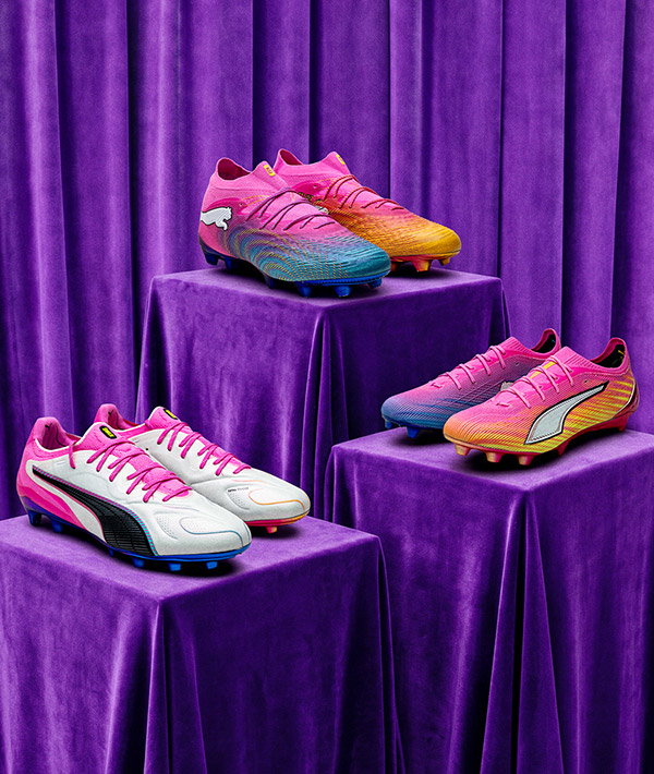Three pairs of colourful football boots (pink, blue and yellow gradients) displayed on purple velvet pedestals