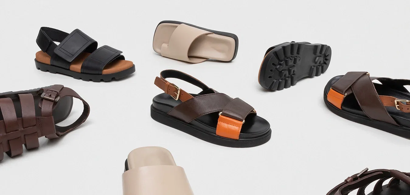 Verschiedene Sandalen aus einer Mischung von Materialien. Die Farben umfassen Braun, Schwarz und Beige. Die Designs variieren mit Riemen und strukturierten Sohlen.