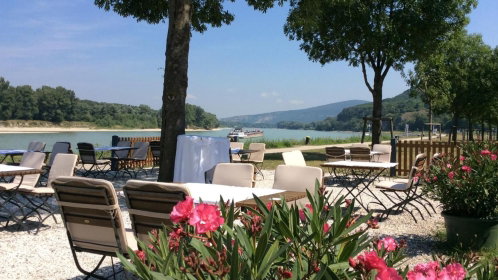 Hotel Gastgarten mit Stühlen und Tischen und Blick auf die Donau
