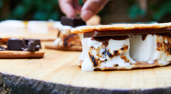 S'mores with roasted marshmallows sit at a campsite