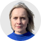 Lorna Gordon looks at the camera. She wears a blue top and has light coloured hair. The background is plain grey.