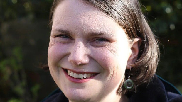 A close-up of Sarah Wakefield, who has short brown hair and is wearing green earrings.