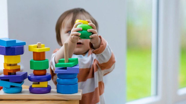 A nursery-age child plays with colourful building blocks.