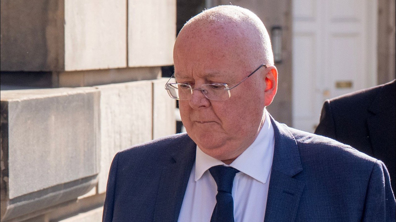Peter Murrell casts his eyes downwards as he walks past Edinburgh High Court. He wears glasses, a dark blue blazer, tie and white shirt.