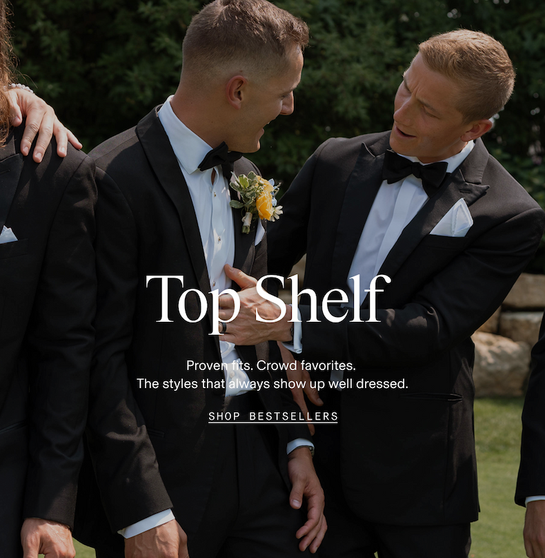 Two groomsmen in black tuxedos with bow ties and boutonnieres laughing together outdoors at a wedding. Top Shelf. Proven fits. Crowd favorites. The styles that always show up well dressed. SHOP BESTSELLERS