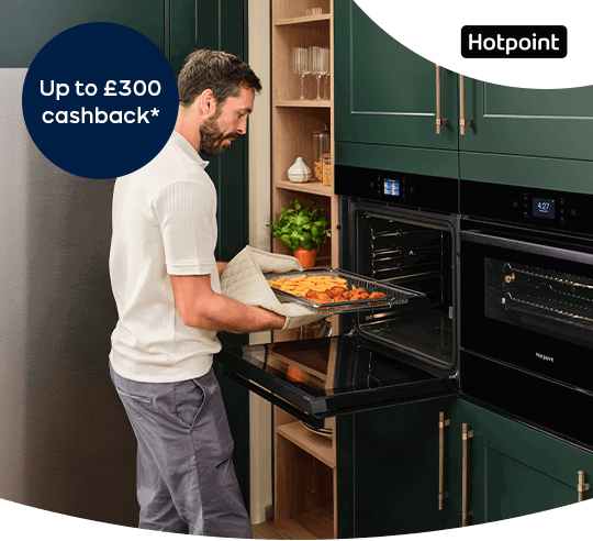 A man putting a tray of food into an oven.