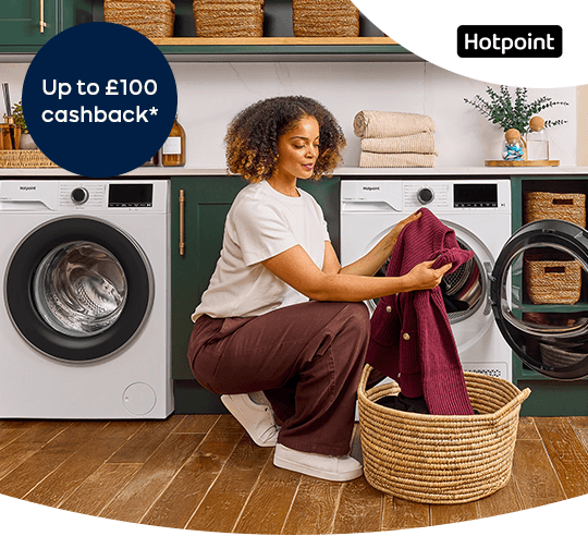 A woman taking laundry out of a tumble dryer.
