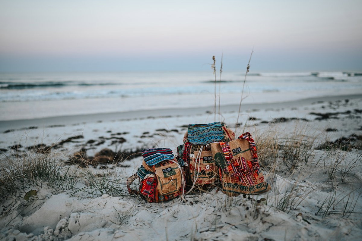 Three Rice Love OOAK bags on a sandy beach at dusk with ocean in the background