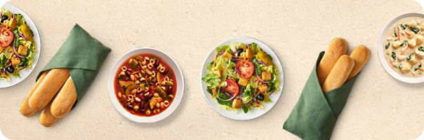 Olive Garden breadsticks, soup, salad, and pasta dishes arranged across a table.
