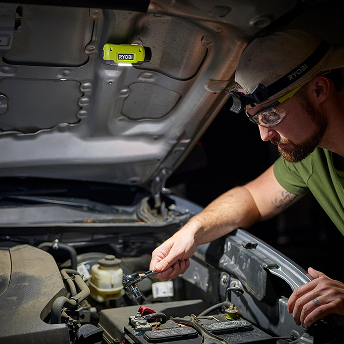 Man using headlamp attached to car hood