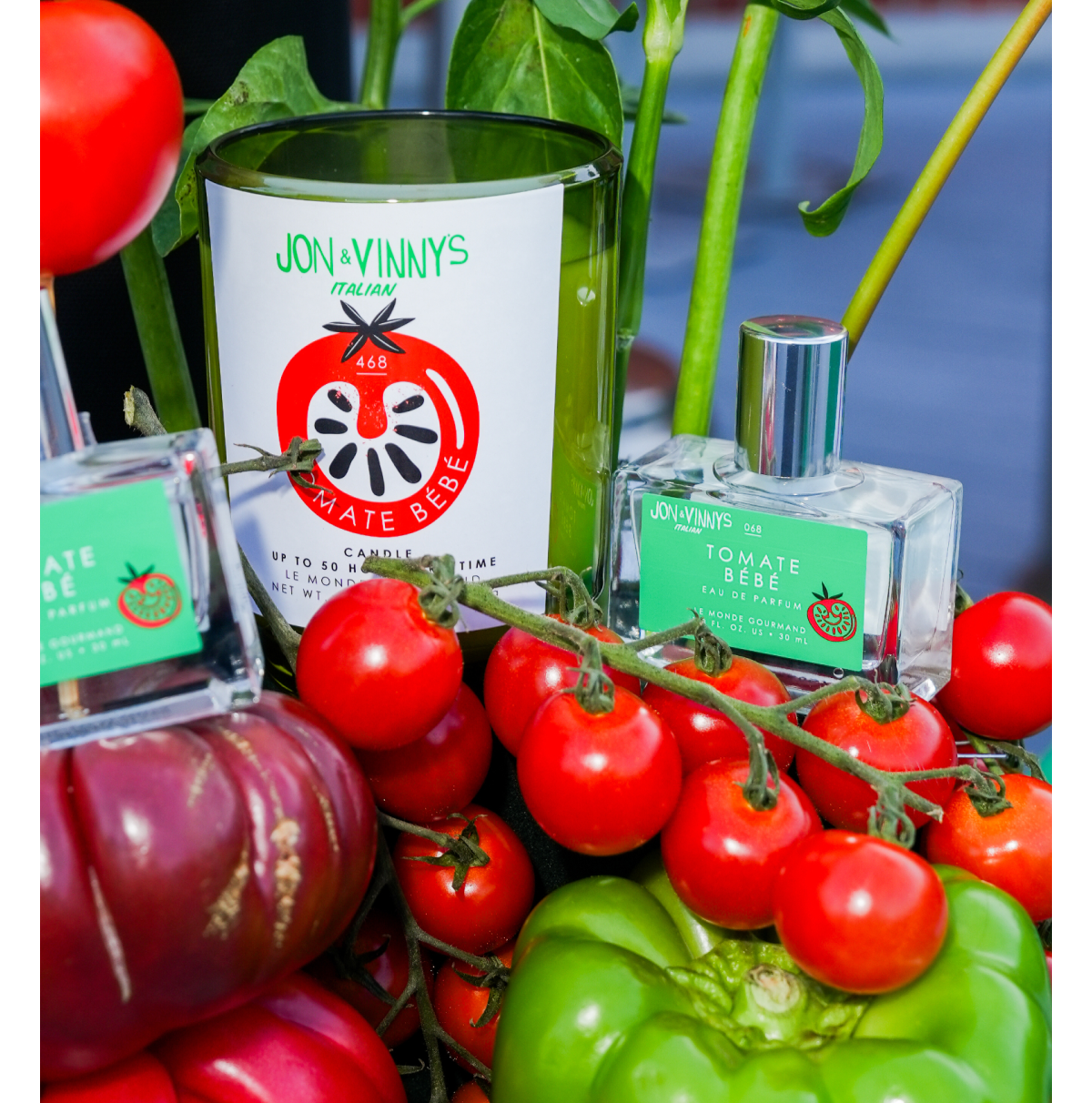Jon & Vinny’s Italian x Le Monde Gourmand collaboration campaign image featuring Tomate Bébé fragrance and candle displayed amongst fresh tomatoes and green peppers.