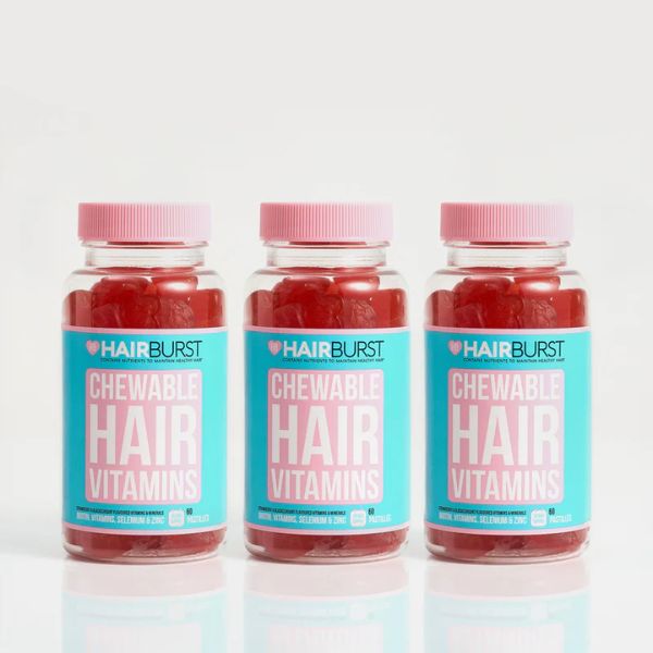 Three bottles of Hairburst Chewable Hair Vitamins with pink lids and blue labels.