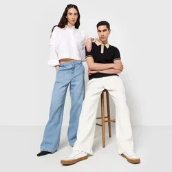 Deux mannequins se tiennent côte à côte. L'un porte une chemise courte blanche et un jean large bleu ; l'autre porte un polo noir et un pantalon blanc.