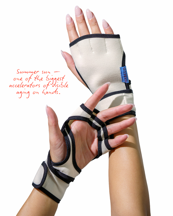 Editorial image of hands wearing ivory Habelo Treatment-Boosting Gloves with black trim and blue logo tag detail. Red handwritten text reads: ‘Summer sun — one of the biggest accelerators of visible aging on hands.