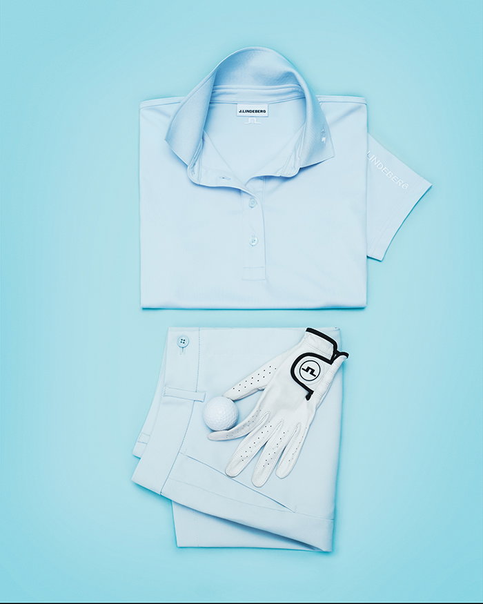 flat lay of a blue polo blue shorts and white golf glove against a blue backdrop link to womens tour tech polo