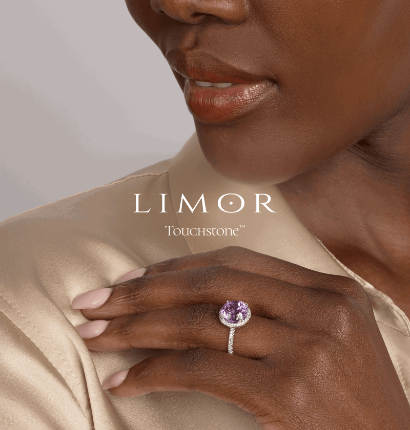 Close-up of female model wearing oval purple amethyst halo ring with diamond pavé band. Limor Touchstone logo.