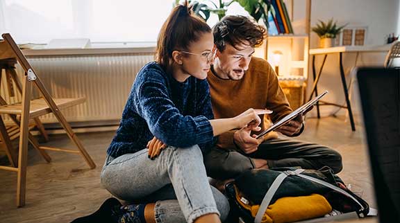 Paar sitzt auf dem Boden und schaut auf ein Tablet