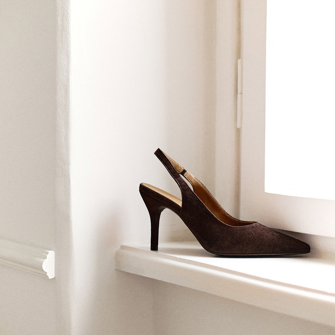 Elegant brown suede slingback high heel shoe on window ledge