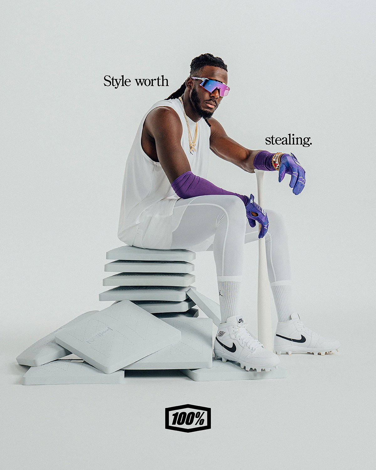 Elly De La Cruz in all white sitting on a pile of bases featuring his new campaign 'Style Worth Stealing' for his new signature edition 100Percent eyewear collection.