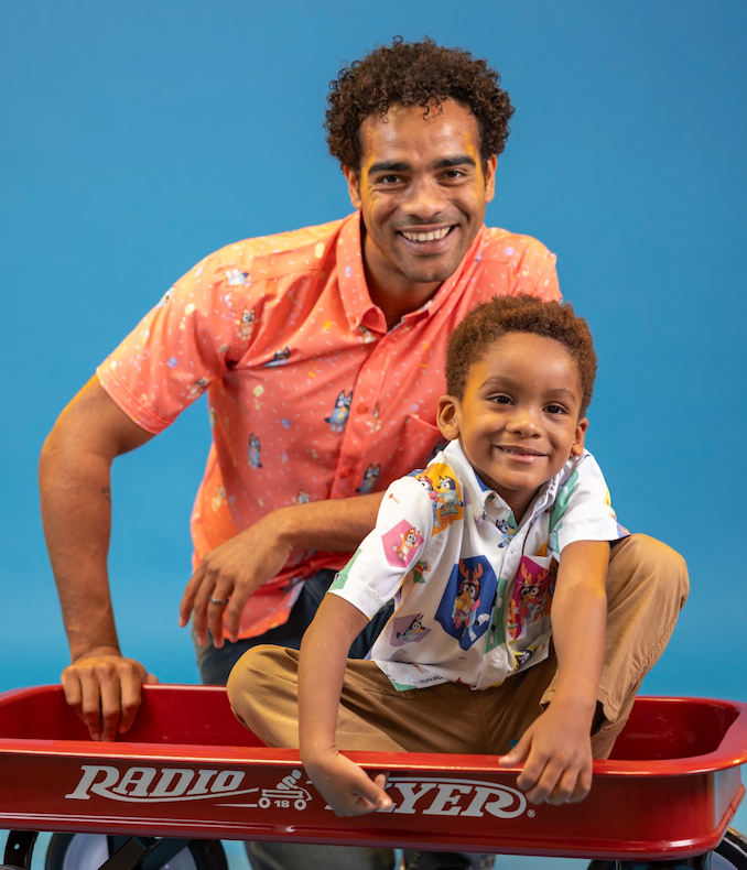 Man standing behind child in little red wagon