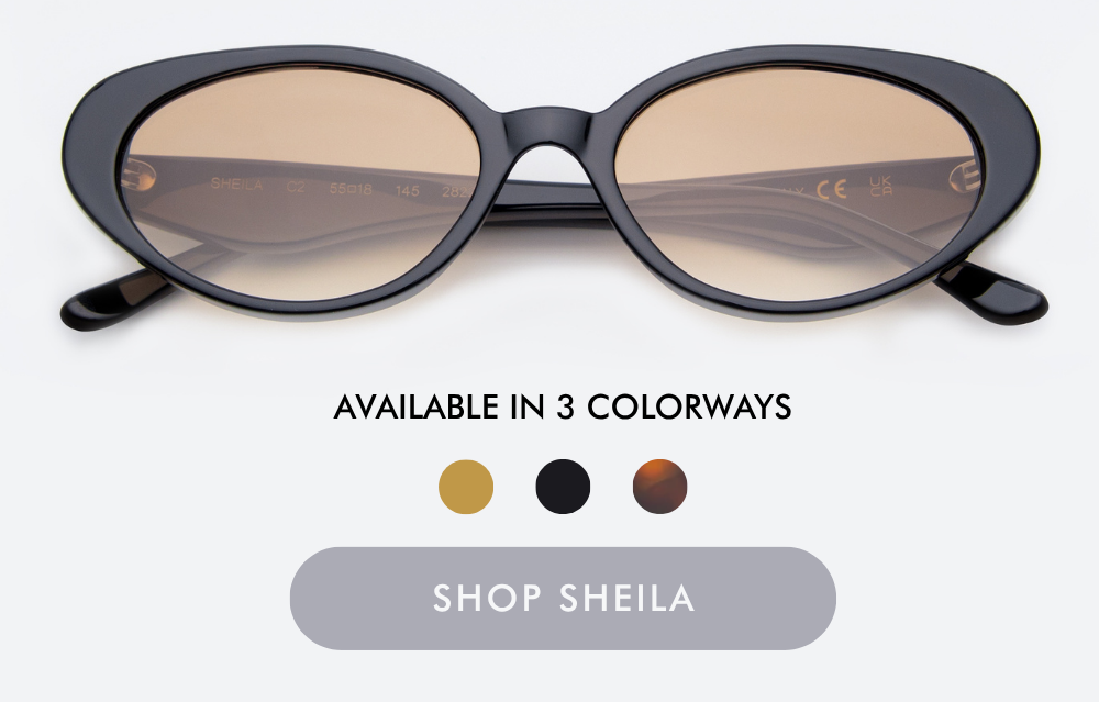 A studio product shot of the Prince Tate sunglasses, featuring a polished gold metal frame paired with clear, translucent beige acetate inner rims and dark grey lenses. Below the glasses, text reads 