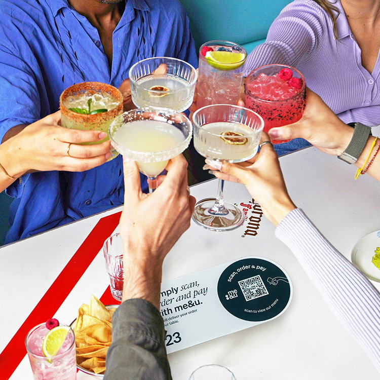 Image of people holding drinks at a me&u venue table