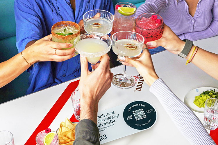 Image of people holding drinks at a me&u venue table